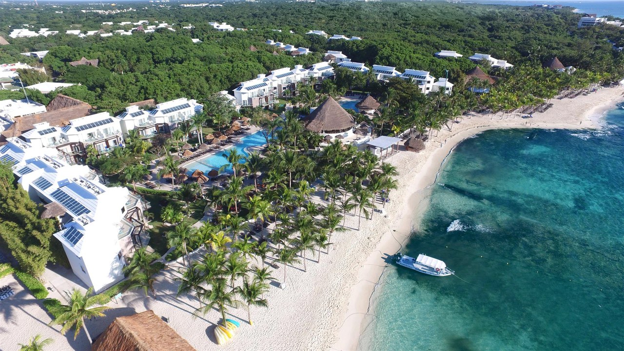 Aerial view of a palm-lined beach and pools at an all-inclusive resort on Mexico's Riviera Maya
