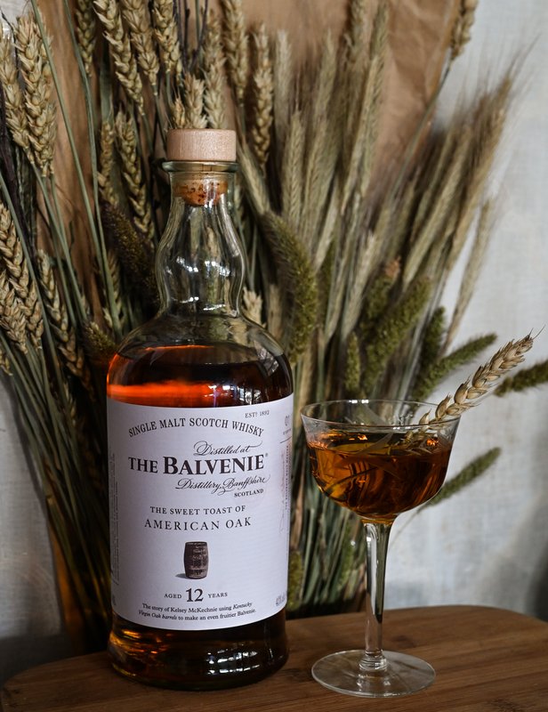 The Balvenie Harvest Honey cocktail in a coupe beside a bottle of The Balvenie 12