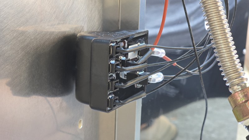Close-up of the Kenmore grill's ignition module and wiring harness during assembly, with individual wires plugged in by hand