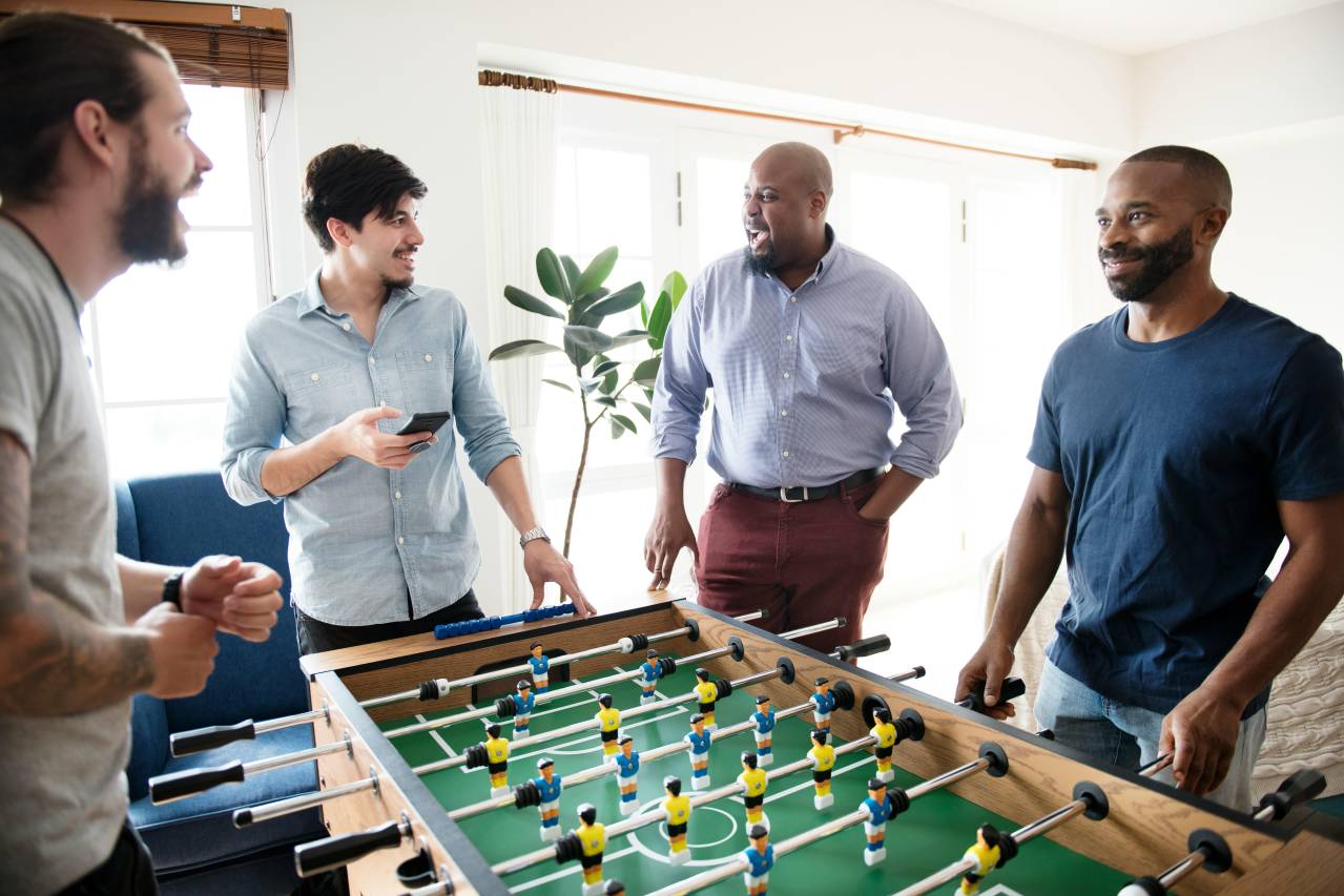 group of men playing foosball in a man cave