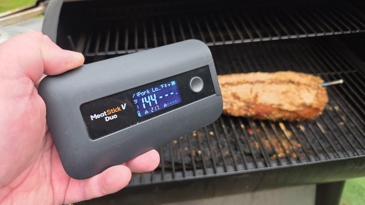 MeatStick V Duo Smart Base displaying 144°F next to a smoked pork loin on the grill