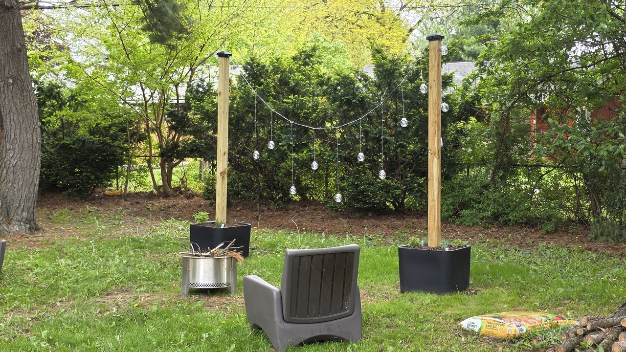 Step2 Firefly String Light Pole Stand with Planter installed in a backyard hangout zone with Solo Stove firepit and Step2 Switchback patio chair