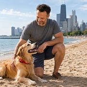 A dad kneeling beside his golden retriever on a Chicago lakefront beach