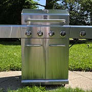 Kenmore 4-Burner Gas Grill with Side Searing Burner in stainless steel, lid closed, on a backyard patio