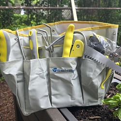 Yesker 10-piece garden tool set loaded in its gray and yellow tool bag on a raised bed next to a basil plant