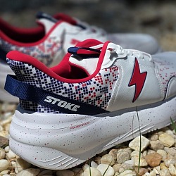 Stoke FO-MO 2Fiddy wide sneakers in red, white, and blue resting on gravel
