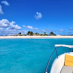 A private charter boat anchored off Sandy Island near Anguilla, with a white sand beach bar and turquoise water ahead