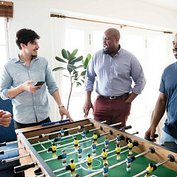 group of men playing foosball in a man cave