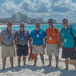 A group of men enjoying their all-inclusive Cancun resort, relaxing on the beach with their resort in the background.